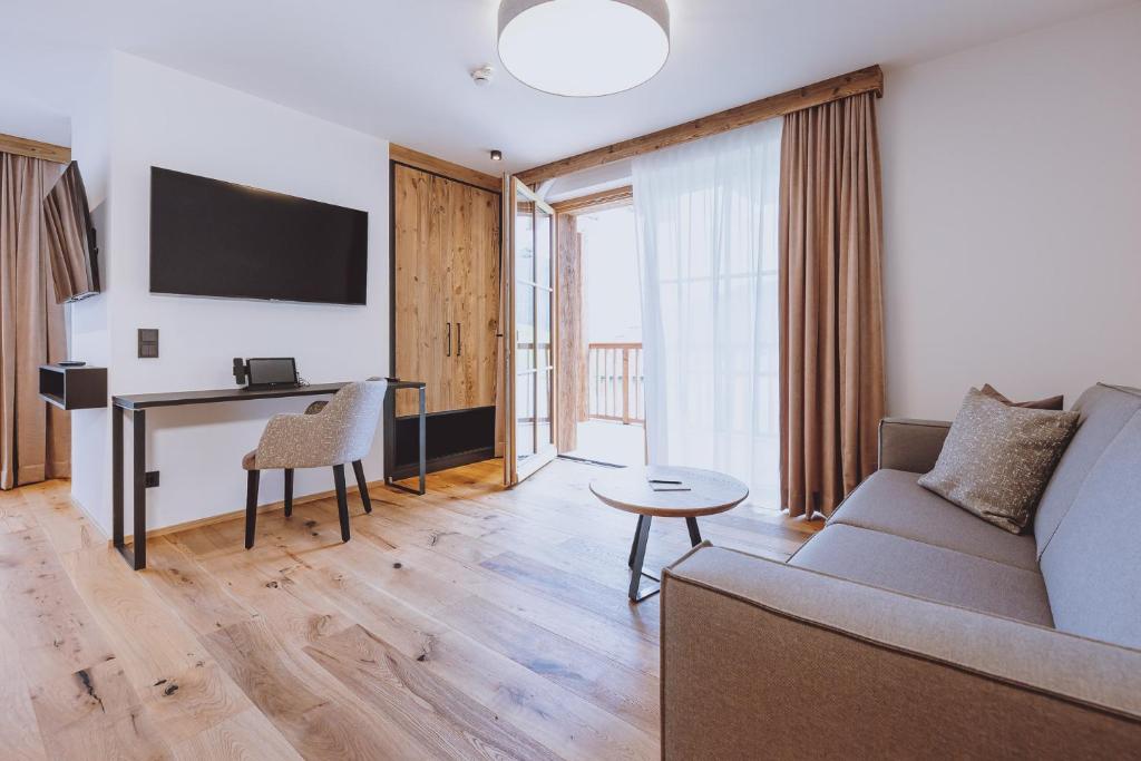 a living room with a couch and a desk at Bergdorf Hotel Zaglgut in Kaprun