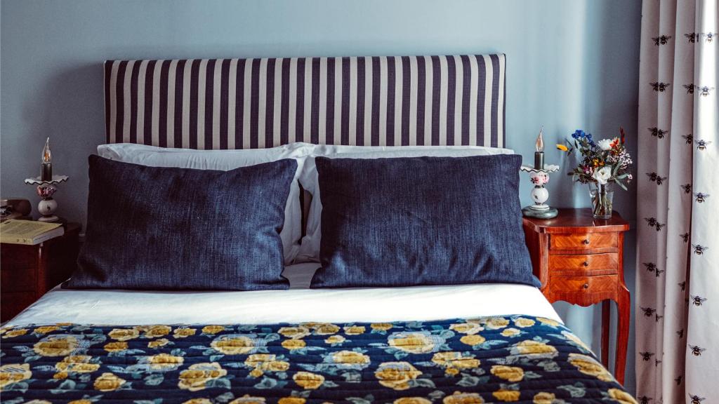 a bed with two blue pillows and a striped headboard at Maison Saintonge in Paris