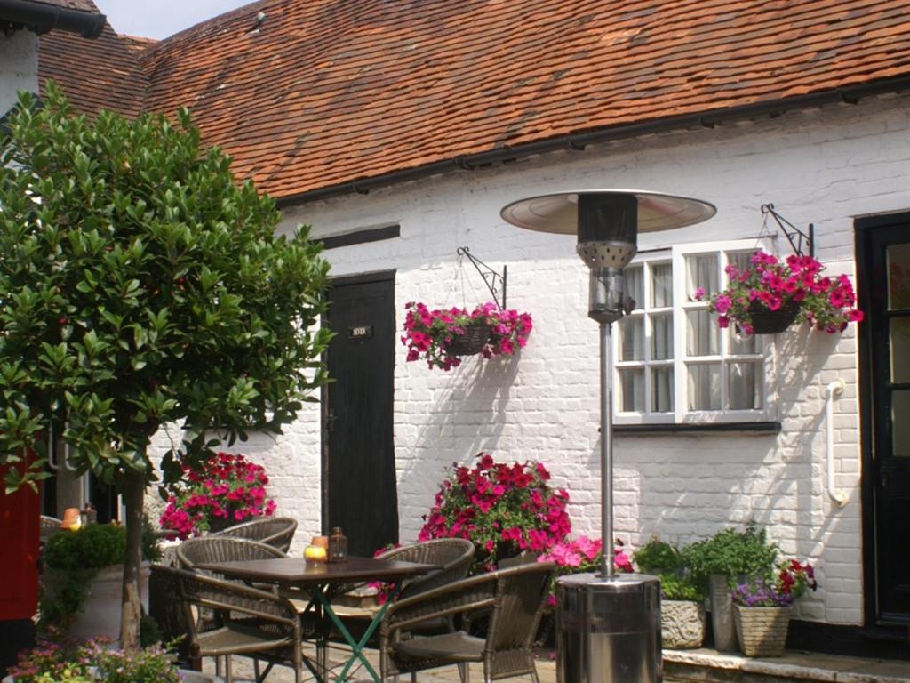 una mesa y sillas frente a una casa con flores en THE SARACENS HEAD INN, en Amersham