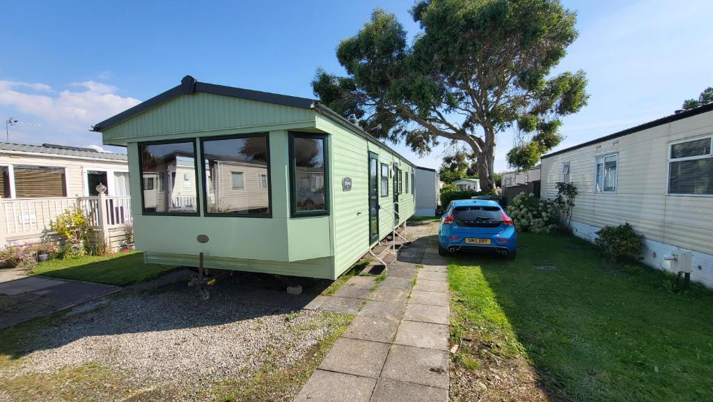 a green tiny house parked next to a car at 19 Barnacre Scorton in Scorton