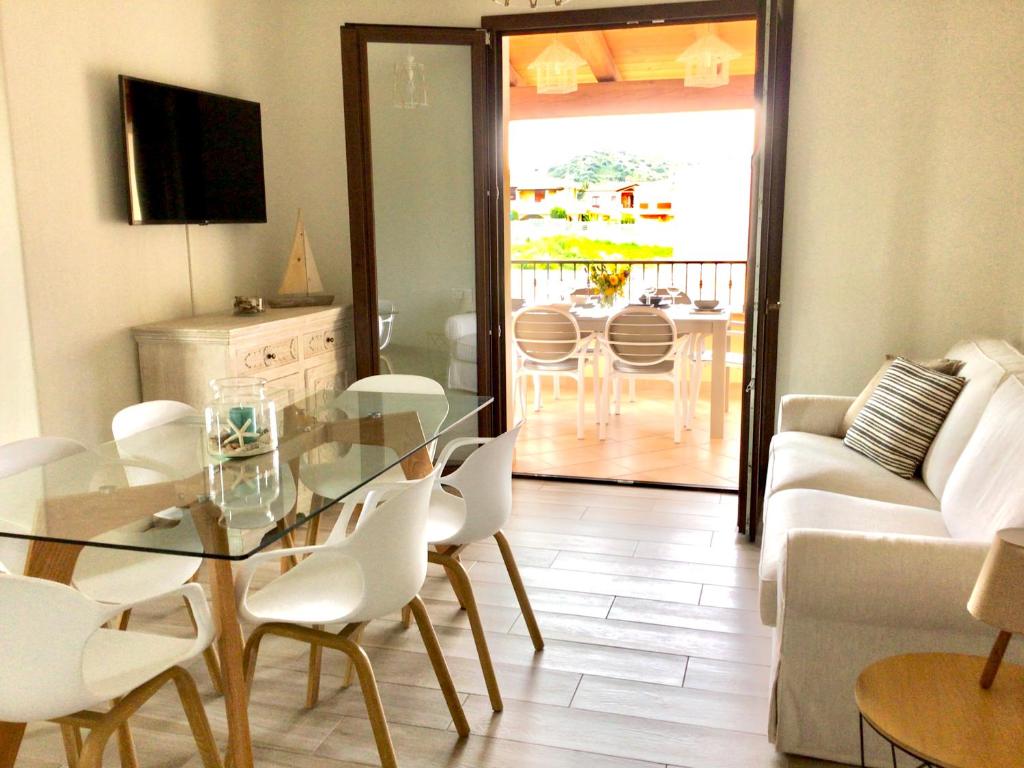 a living room with a glass table and white chairs at Oasi delle Onde in Villasimius