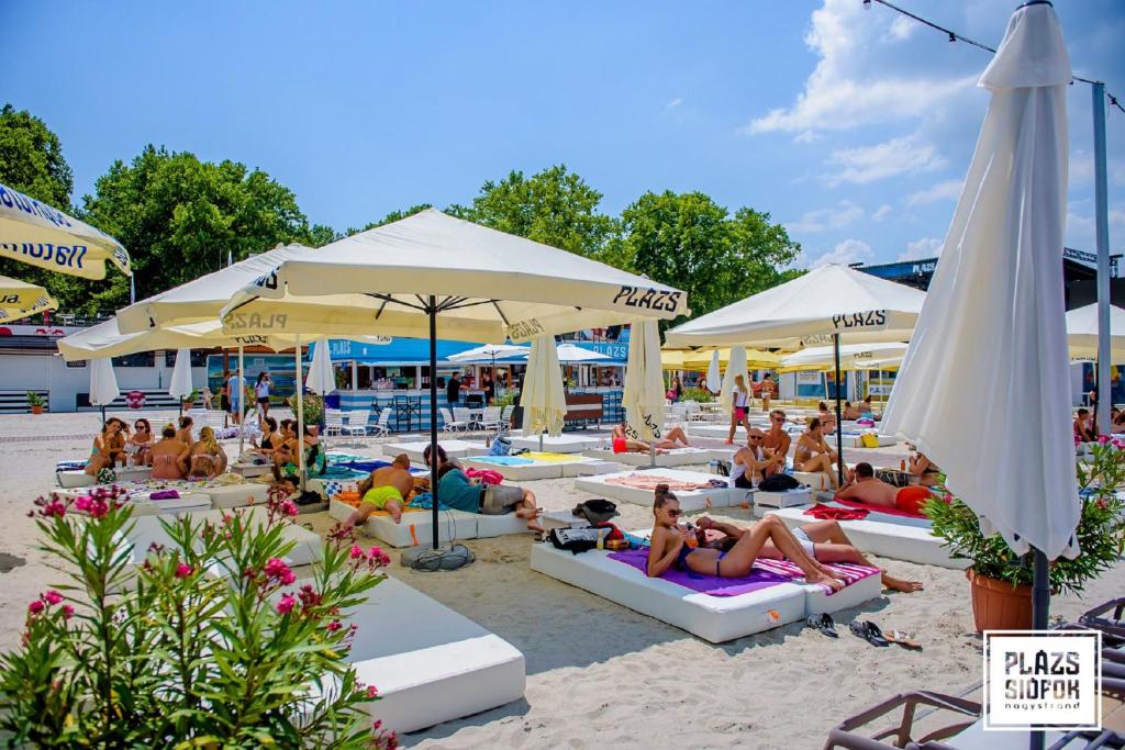 grupa ludzi siedzących na plaży z parasolami w obiekcie Holiday home in Siofok - Balaton 43127 w Siófoku