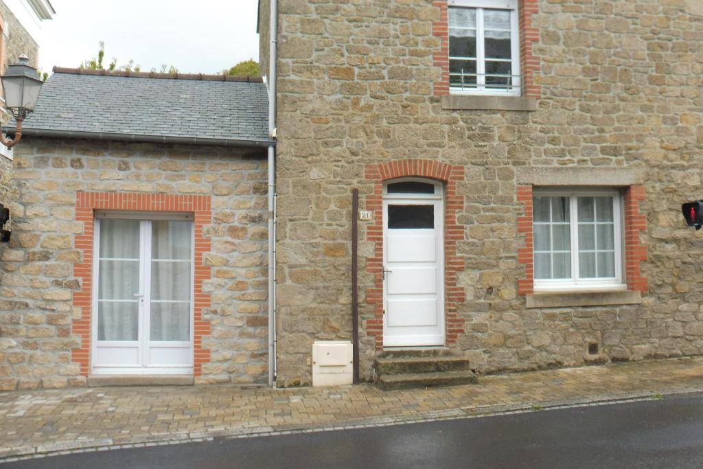 a brick building with two windows and a white door at Maison Saint-Coulomb in Saint-Coulomb