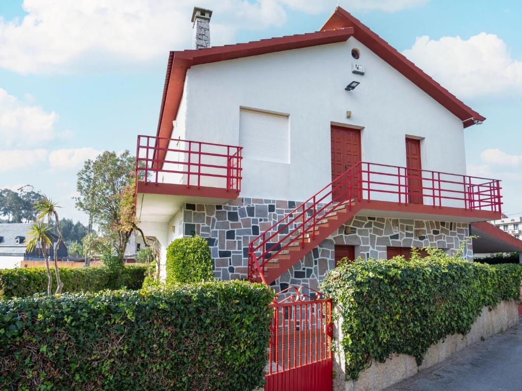 ein weißes Haus mit rotem Geländer und Büschen in der Unterkunft Charming holiday home in Sanxenxo with private terrace in Sanxenxo