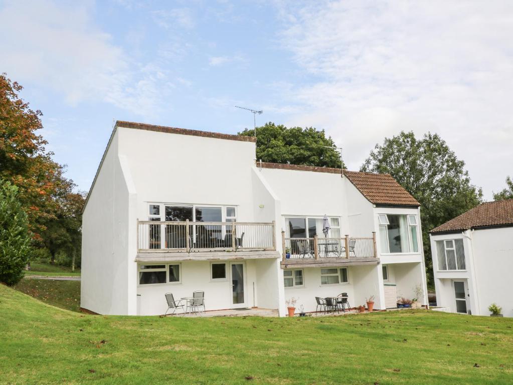 ein weißes Haus auf einem Hügel mit Stühlen in der Unterkunft Patch's Place in Gunnislake
