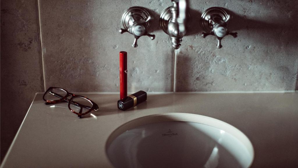 a urinal with a red candle and glasses on a counter at Maison Saintonge in Paris