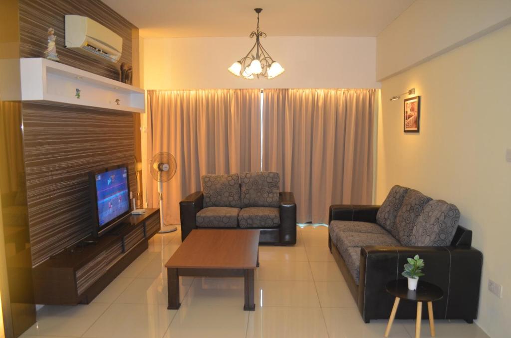 sala de estar con sofá y TV en Bougainvillea KintaRiverfront en Ipoh
