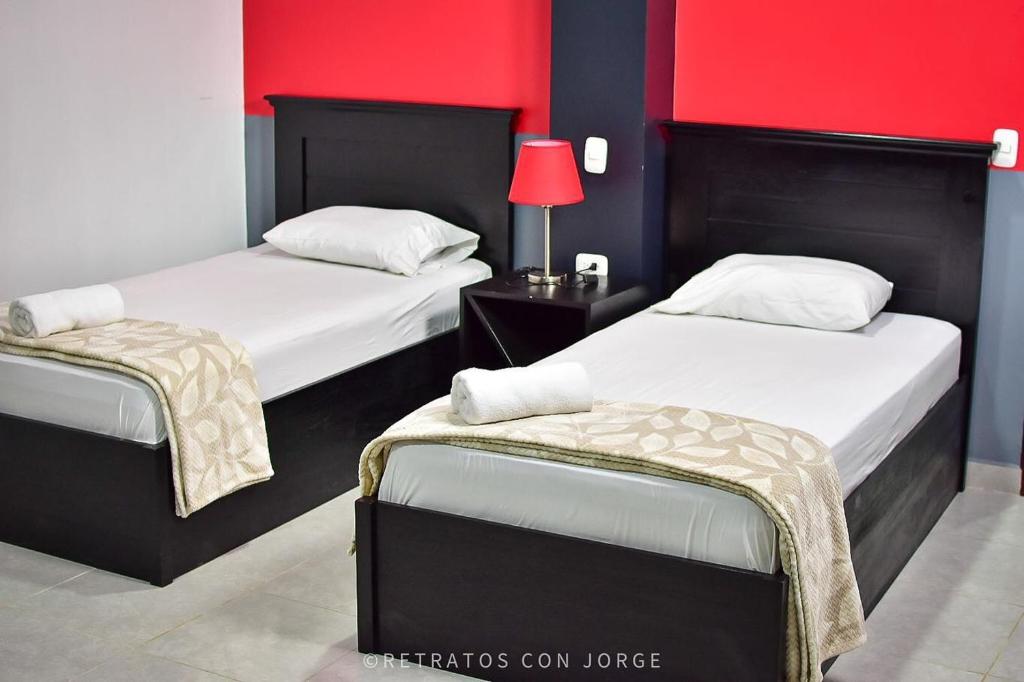 1 dormitorio con 2 camas y pared roja en Diesbu Hotel, en Marcala