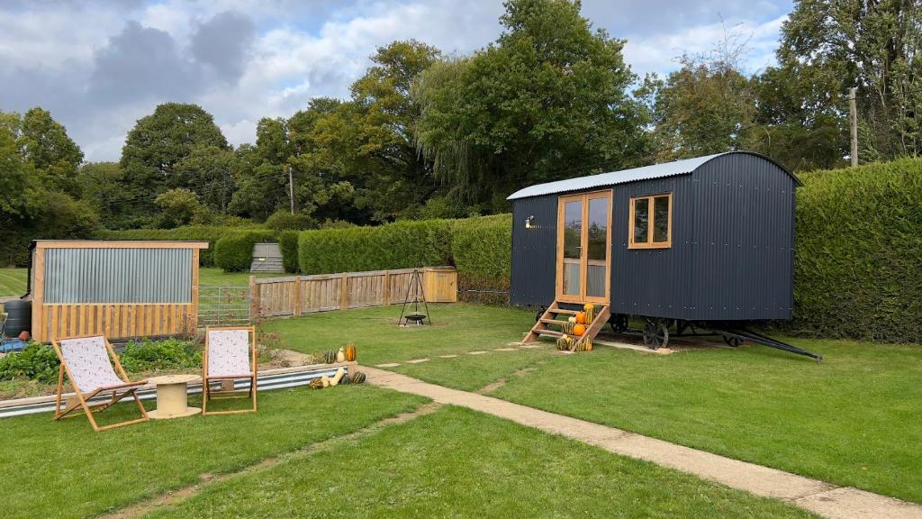 une petite maison bleue assise au-dessus d'une cour dans l'établissement Shepherds Hut at Cedar Gables, à Lamberhurst