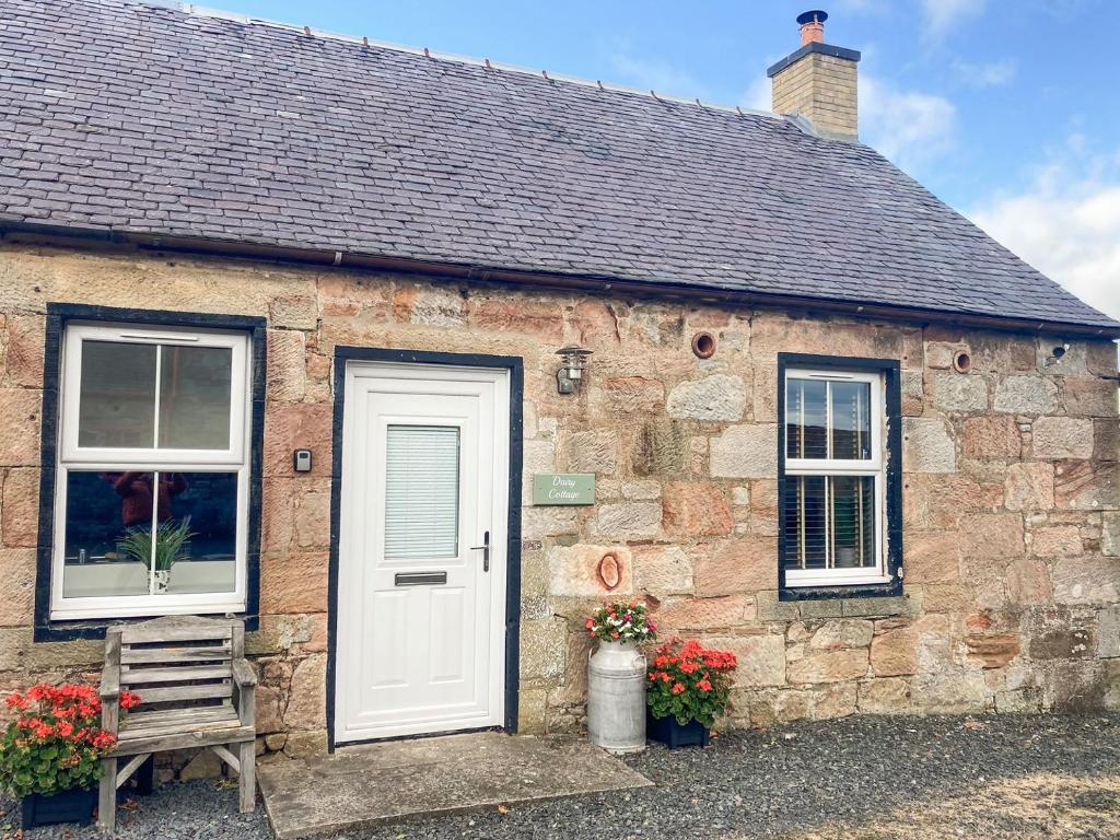 a brick house with a white door and a bench at Dairy Cottage - Uk39522 in Maybole