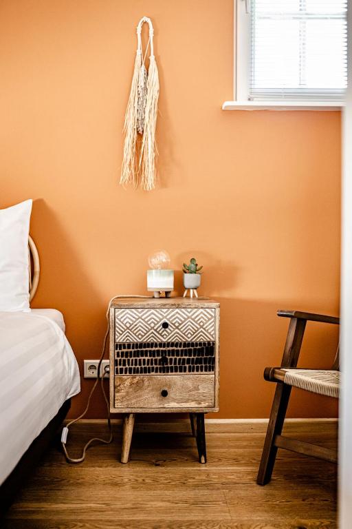 a bedroom with an orange wall with a bed and a night stand at TinyParks Eiland Tiengemeten in Zuid-Beijerland