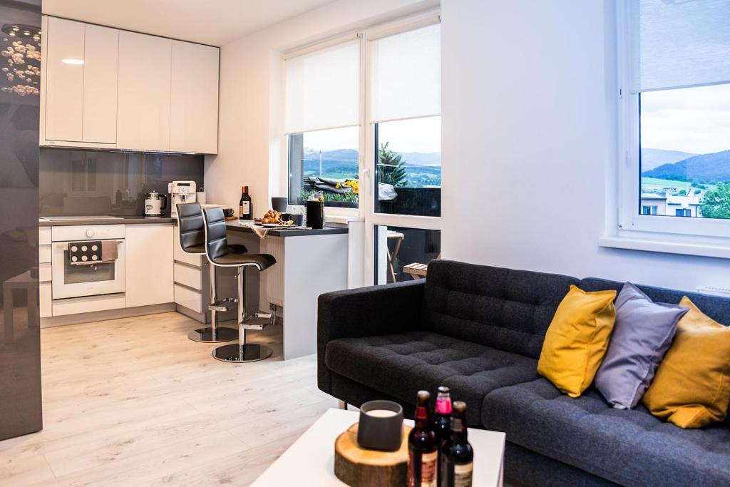 een woonkamer met een bank en een keuken bij Apartment,private parking, balcony, smart check in in Banská Bystrica