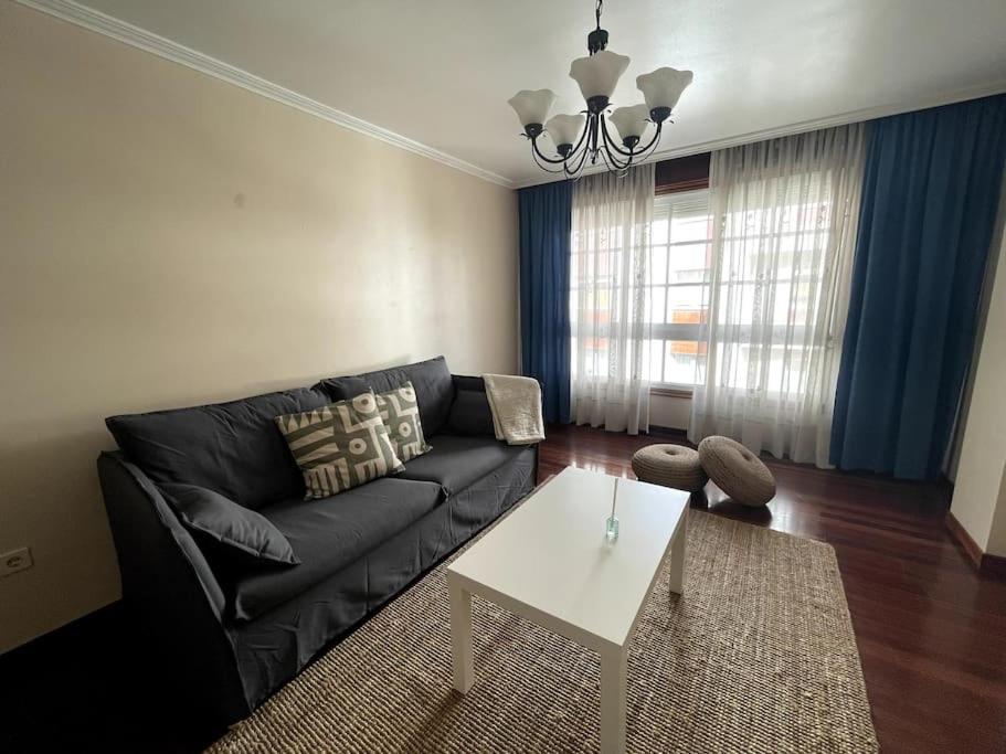 a living room with a black couch and a white table at Agradable apartamento céntrico en Cangas in Cangas de Morrazo