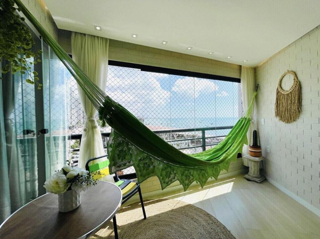 um quarto com uma rede de descanso, uma mesa e uma janela em Flat Luxuoso Alto Padrao Frente Mar com 2 suites no Iate Plaza em Fortaleza