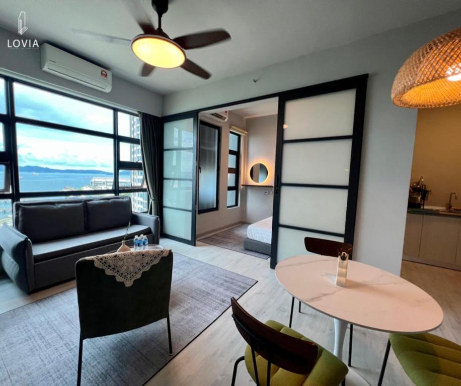 a living room with a couch and a table and chairs at Jesselton Quay KK SEA VIEW or CITY VIEW by LOVIA in Kota Kinabalu