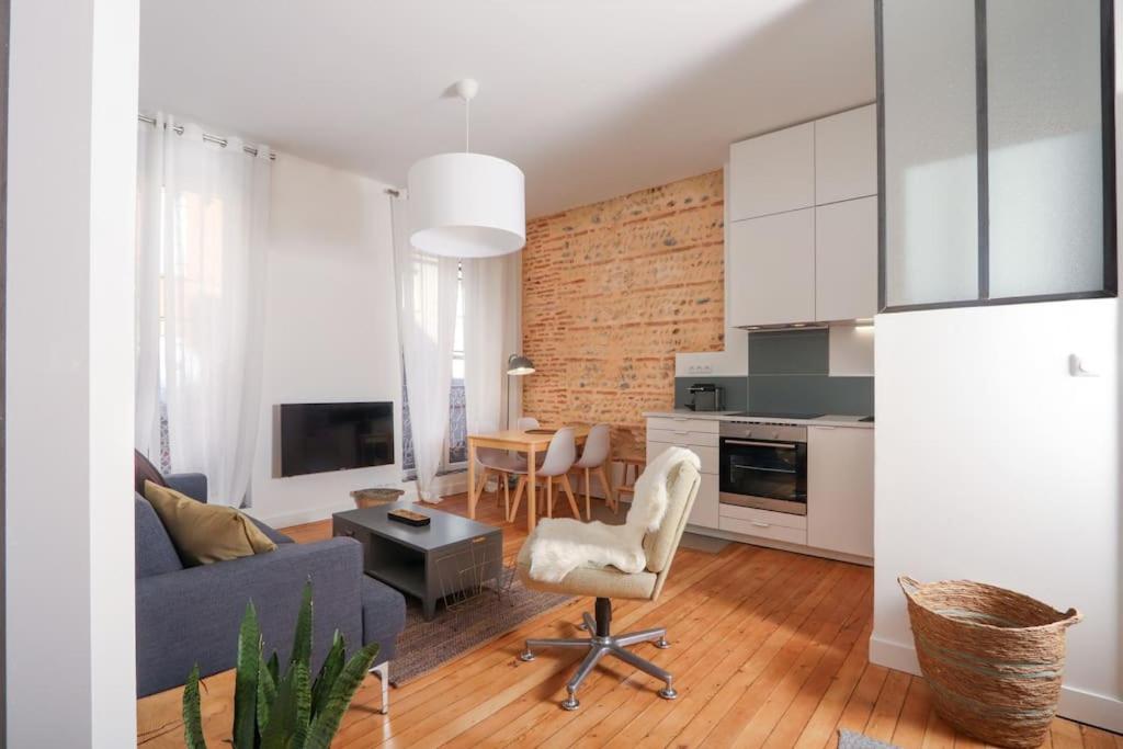 ein Wohnzimmer mit einem blauen Sofa und einer Küche in der Unterkunft Confortable T2 à Saint Aubin in Toulouse