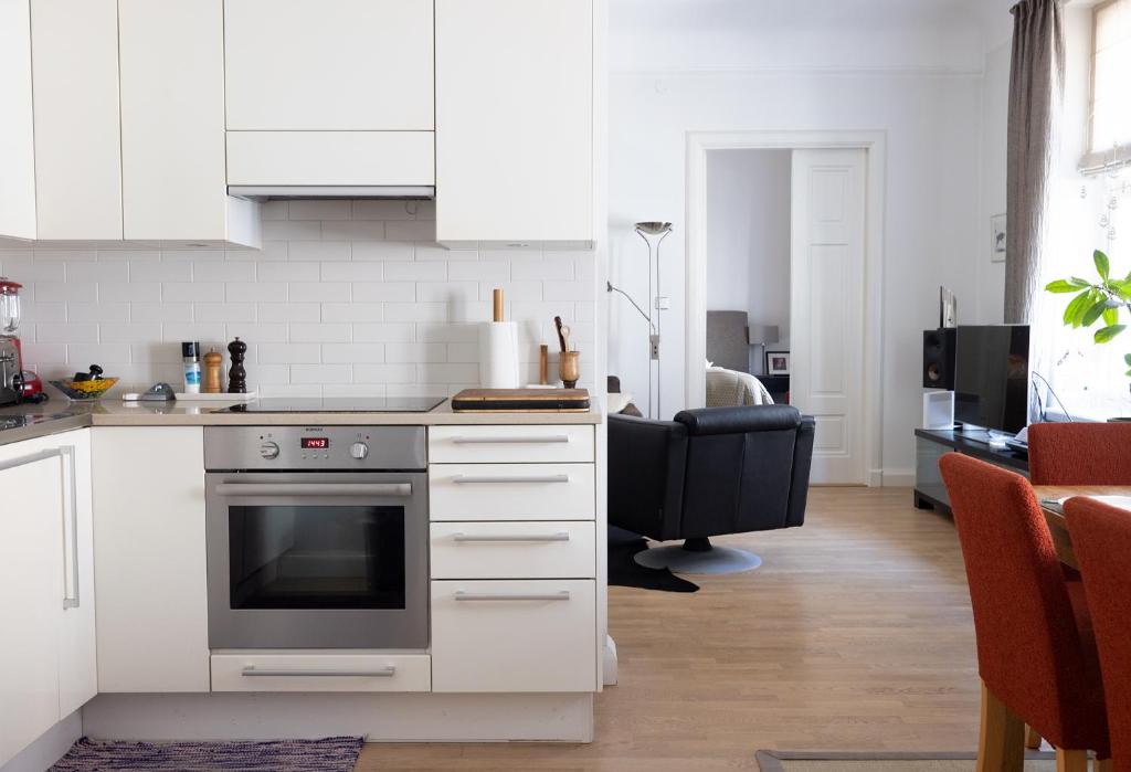 a kitchen with white cabinets and a black chair at 2ndhomes Luxury Helsinki Center 2BR Apartment with Sauna in Helsinki