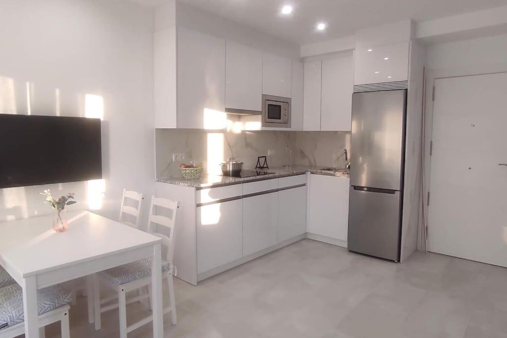 eine Küche mit weißen Schränken und einem Kühlschrank aus Edelstahl in der Unterkunft Precioso apartamento en el corazon de la cala. in Mijas Costa