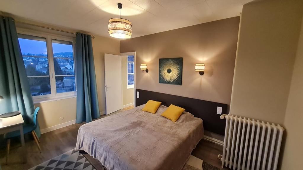 Un dormitorio con una cama con almohadas amarillas y una ventana en Hotel De La Poste, en Mortain