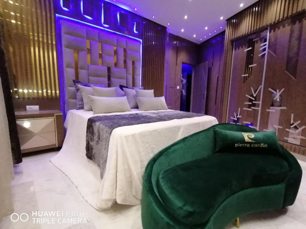 una camera con un grande letto e una sedia verde di Ap 2ch city centre parking en face Hilton a cote du plage a Tangeri