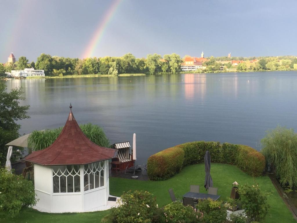 a rainbow over a lake with a gazebo at Ferienzimmer am See in Ratzeburg