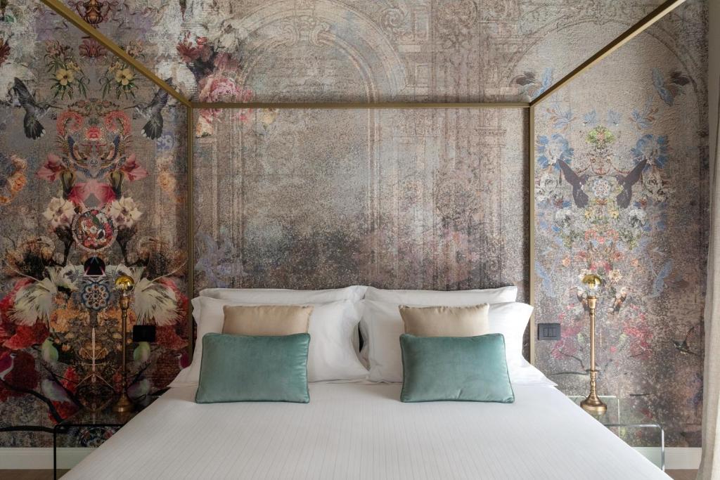 a bed with two pillows in front of a floral wall at Vossia Luxury Rooms & Sicilian Living in Palermo