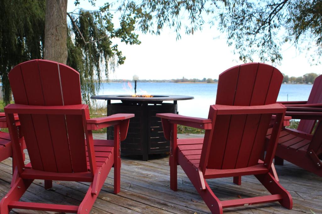 two red chairs and a table on a deck at Bungalow on the Bay in Carrying Place