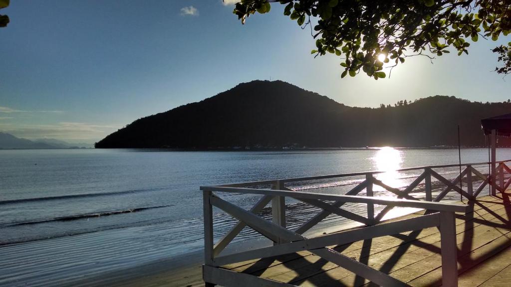 a bench on the beach near the water with a mountain at Boa Vida Ubatuba in Ubatuba