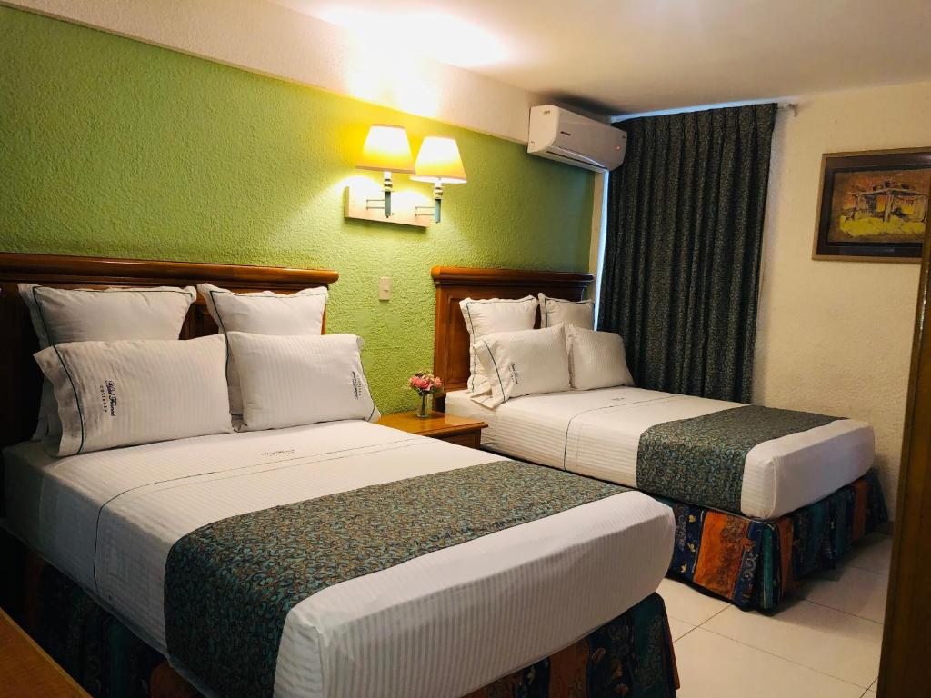 two beds in a hotel room with green walls at Hotel Francis in Culiacán