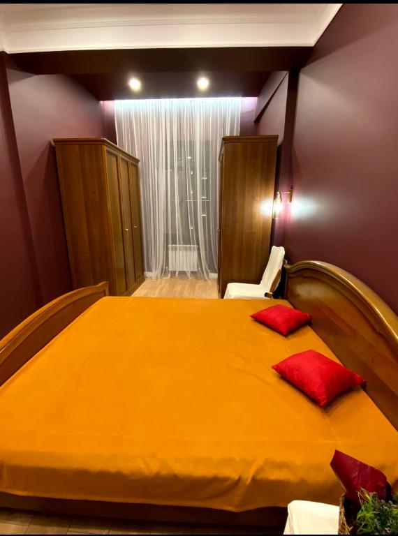 a bedroom with a large yellow bed with red pillows at Квартира студия in Almaty