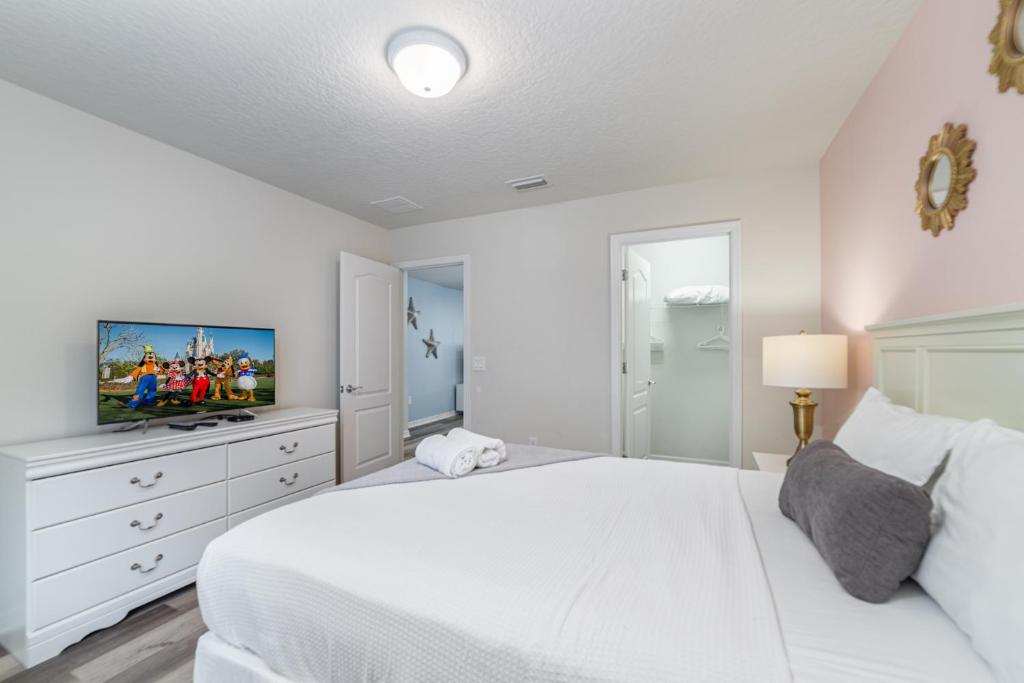 a white bedroom with a white bed and a tv at Blue Stylish Charming Villa with Pool near Disney in Kissimmee
