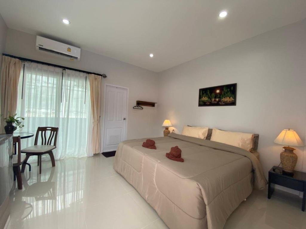a bedroom with a large bed and a table and chair at MONDEE House @The Airport in Thalang