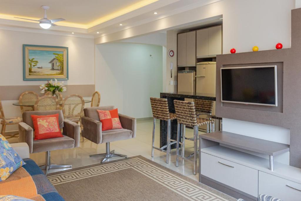 Il comprend un salon avec une télévision et une cuisine avec des chaises. dans l'établissement Apto 2 quartos na Rua 2950, Wifi e Garagem Grande P1232, à Balneário Camboriú