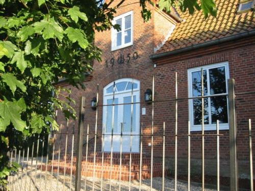 a brick house with a fence in front of it at Hotel Alte Landschule in Langballig