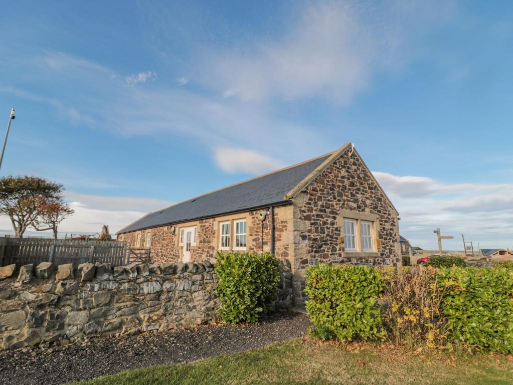 a stone house with a stone wall at Long Cart Cottage in Embleton