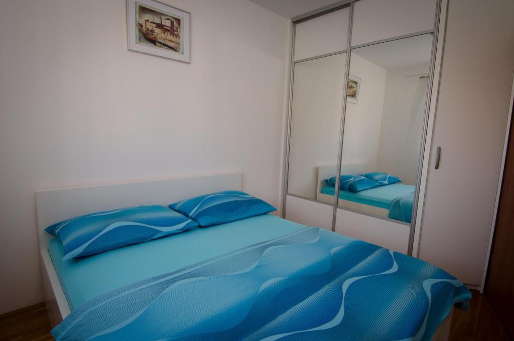 a bedroom with a blue bed and a mirror at Apartments and Rooms Mišić in Trogir
