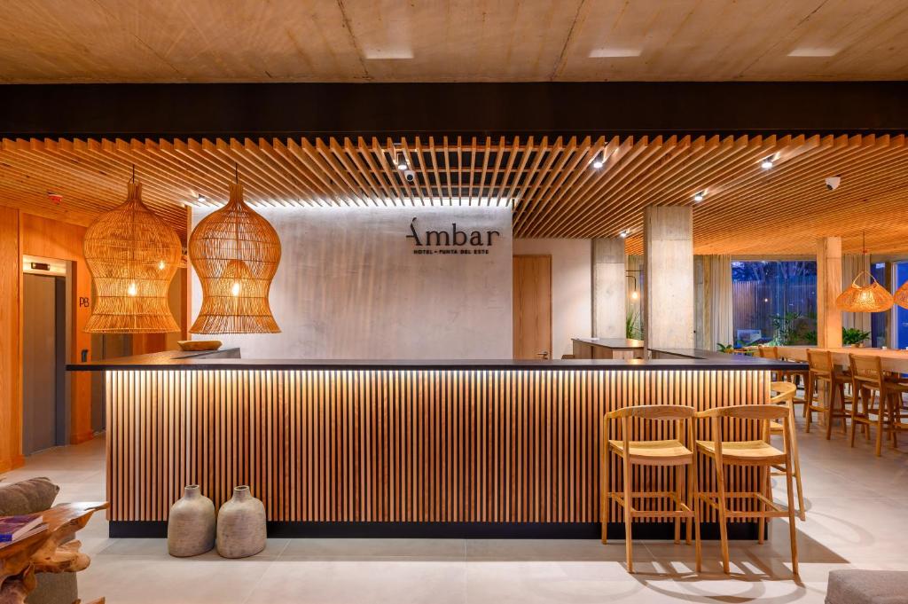 a lobby with a bar with stools and a restaurant at Ambar Hotel in Punta del Este