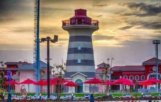 um farol em frente a um edifício com guarda-chuvas vermelhos em Porto Sharm suites & apartments em Sharm el Sheikh