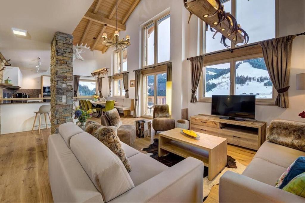 a living room with a couch and a tv and a table at Chalet Ausblicklodge in Mühlbach am Hochkönig