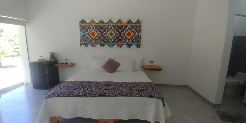 Un dormitorio con una cama y un cuadro en la pared. en Hotel Lucero Chan, en Santa María del Oro