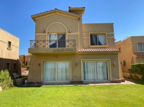 uma casa grande com uma varanda no topo de um quintal em Villa at Piacera Resort-seaview em Ain Sokhna
