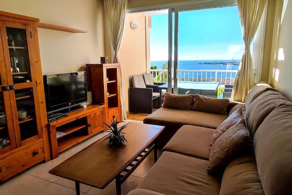 - un salon avec un canapé, une télévision et une table dans l'établissement Beach and pool view , 4 people, and free wifi, à Poris de Abona