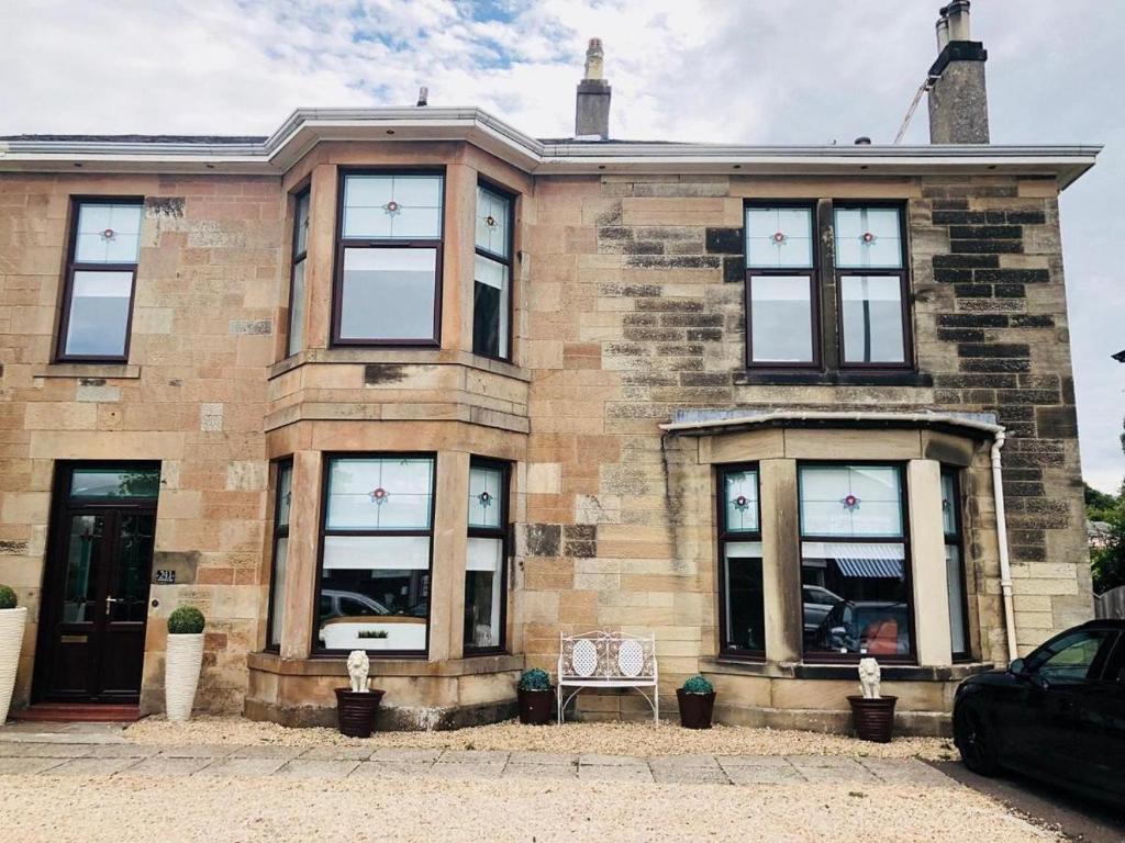 - un bâtiment en briques avec une chaise devant dans l'établissement Giffnock Rooms, à Giffnock