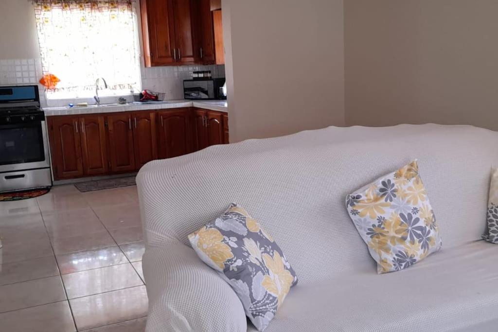 um sofá branco com duas almofadas na cozinha em Ultimate Chill Brown's Town em Browns Town