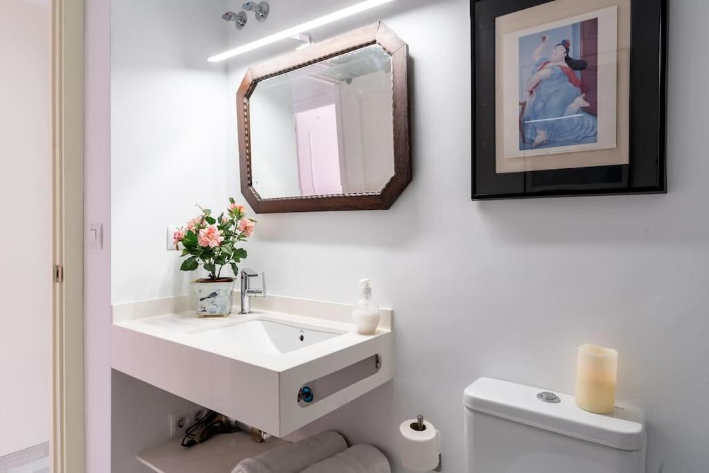 łazienka z białą umywalką i lustrem w obiekcie Apartamentos RG, San Vicente 22 w Sewilli
