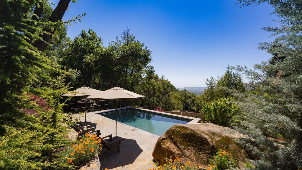 a swimming pool with an umbrella and some trees at Summers House in Sonoma