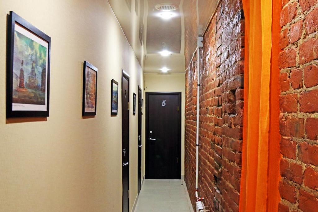a hallway with a black door and a brick wall at Adoriya Apartments in Saint Petersburg