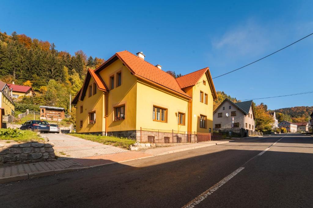a yellow house on the side of a street at Holiday house Vedle in Desná
