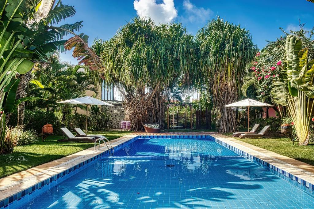 a swimming pool in a yard with chairs and umbrellas at A - Pipa Beleza Unidades Particulares in Pipa