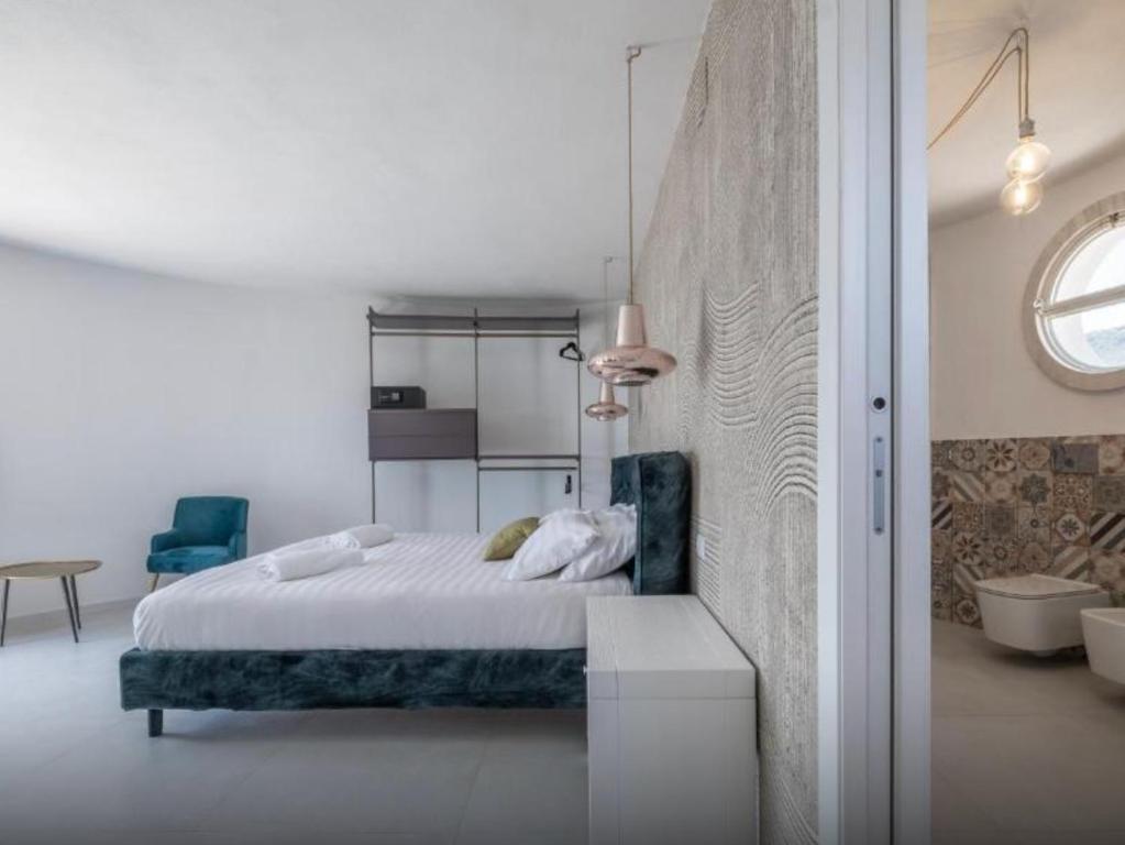 a white bedroom with a bed and a blue chair at Villa Escargot Luxury in Costa Rei Beach in Costa Rei